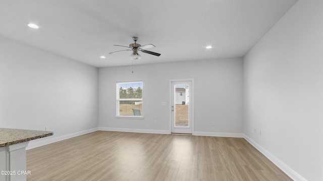 unfurnished living room with light wood-type flooring, ceiling fan, baseboards, and recessed lighting