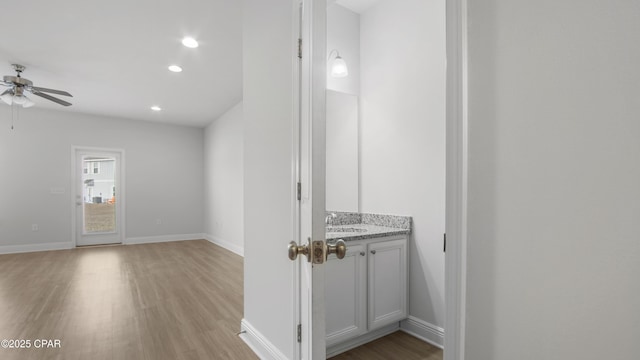 interior space featuring ceiling fan, light wood-style flooring, recessed lighting, a sink, and baseboards