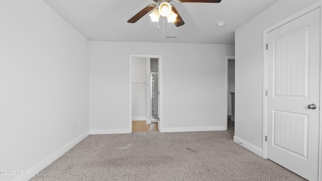 unfurnished bedroom with ceiling fan, carpet floors, visible vents, baseboards, and a spacious closet