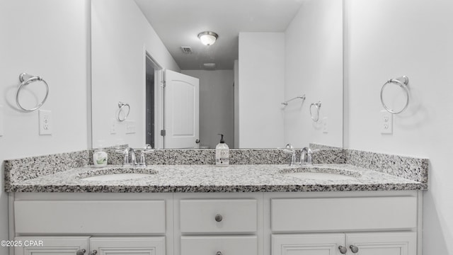 bathroom with double vanity, a sink, and visible vents