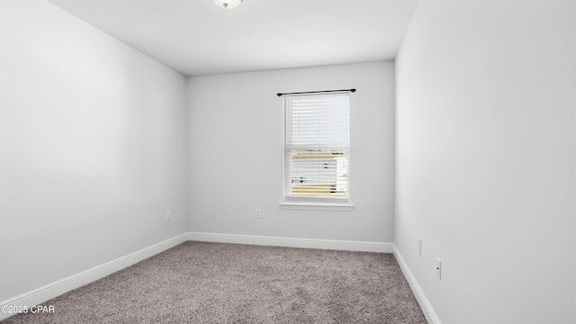 carpeted spare room featuring baseboards