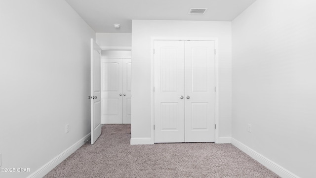 unfurnished bedroom featuring a closet, carpet flooring, visible vents, and baseboards