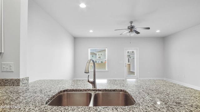 kitchen featuring ceiling fan, recessed lighting, a sink, baseboards, and light stone countertops