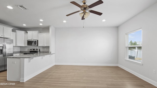 kitchen featuring a breakfast bar, visible vents, appliances with stainless steel finishes, white cabinetry, and a peninsula