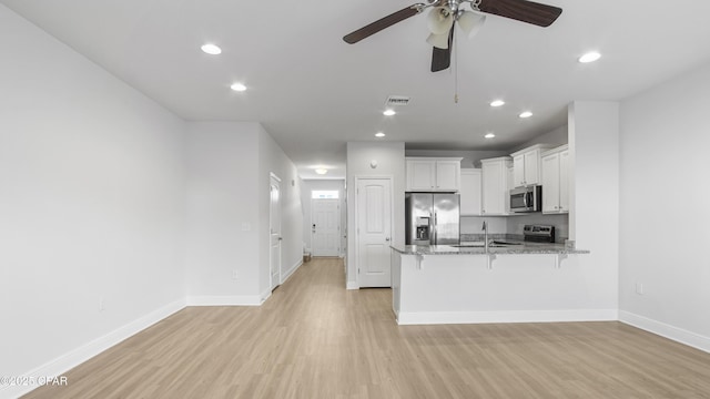 kitchen with visible vents, appliances with stainless steel finishes, a breakfast bar area, a peninsula, and white cabinetry