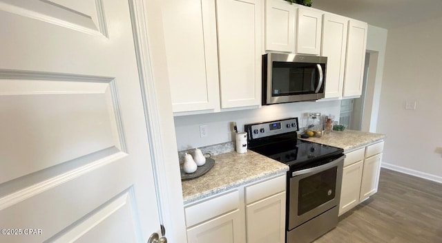 kitchen with stainless steel appliances, light hardwood / wood-style floors, and white cabinets