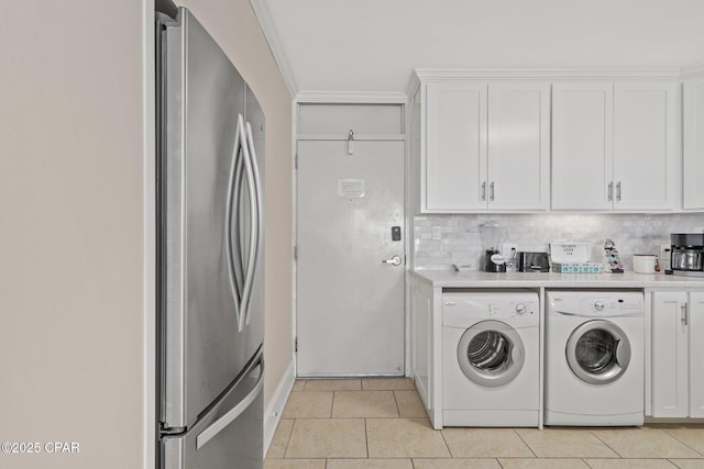 clothes washing area featuring ornamental molding, laundry area, washer and clothes dryer, and light tile patterned floors