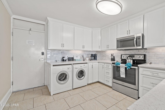 kitchen with washing machine and clothes dryer, stainless steel appliances, light countertops, backsplash, and white cabinetry