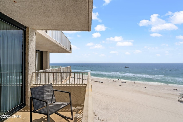 balcony with a water view and a view of the beach