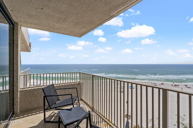 balcony with a water view and a view of the beach