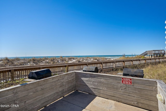 view of patio / terrace with a water view, a grill, and a view of the beach