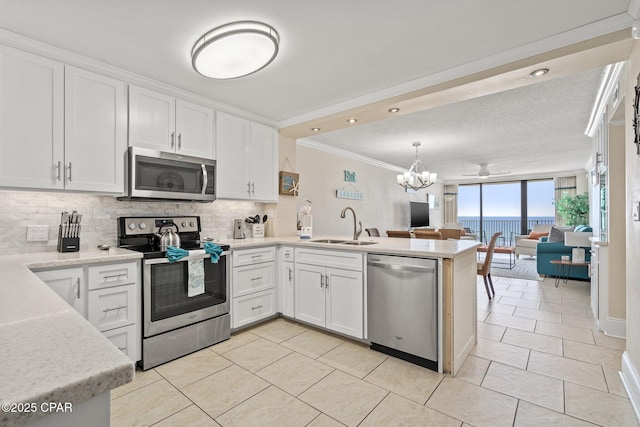 kitchen featuring a peninsula, a sink, white cabinetry, open floor plan, and appliances with stainless steel finishes