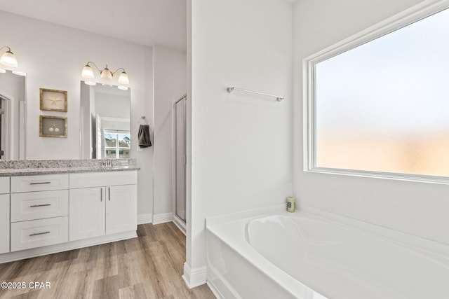 bathroom featuring hardwood / wood-style flooring, vanity, and plus walk in shower