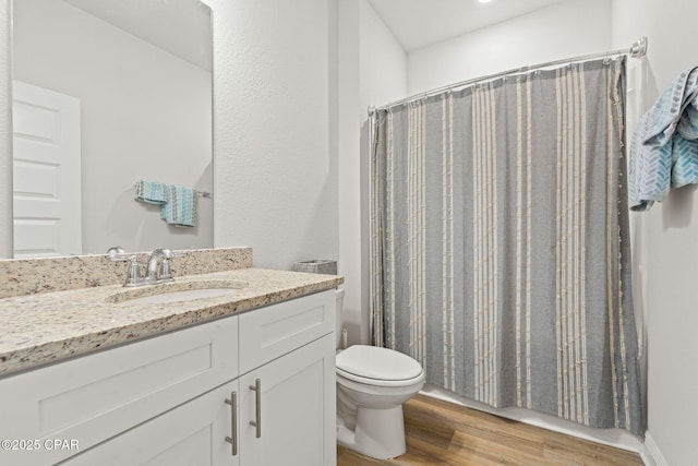 bathroom with toilet, hardwood / wood-style flooring, vanity, and walk in shower