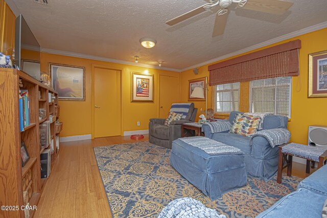 living room with crown molding, ceiling fan, light hardwood / wood-style flooring, and a textured ceiling