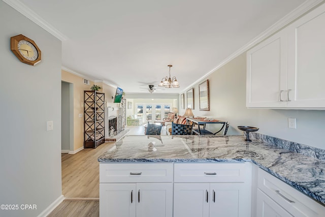 kitchen featuring crown molding, light stone countertops, and white cabinets