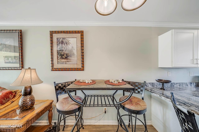 dining area featuring ornamental molding, wood-type flooring, and breakfast area