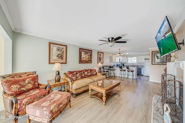 living room featuring ceiling fan, ornamental molding, and light hardwood / wood-style floors