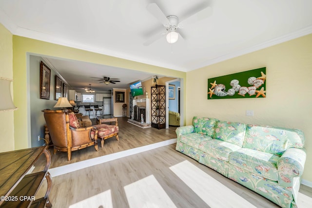 living room featuring crown molding, ceiling fan, and light wood-type flooring