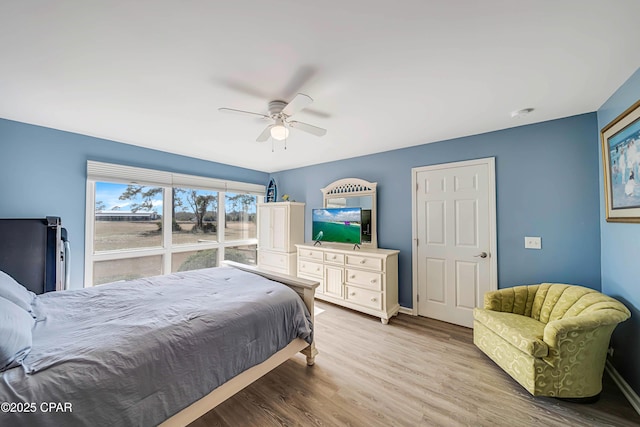 bedroom with fridge, ceiling fan, and light wood-type flooring