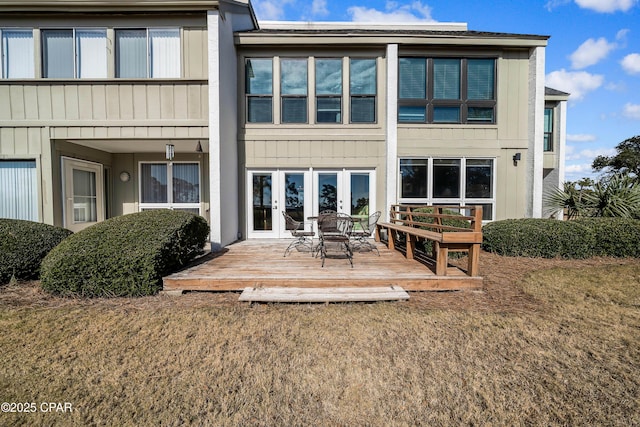 rear view of house featuring french doors, a deck, and a lawn