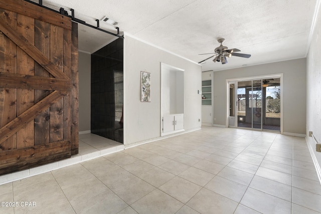 spare room featuring a barn door, light tile patterned floors, built in features, and a textured ceiling