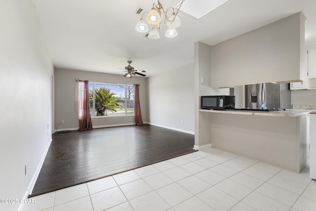 interior space featuring ceiling fan with notable chandelier and light tile patterned floors