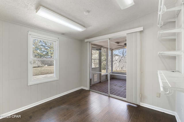 unfurnished room featuring vaulted ceiling, dark hardwood / wood-style floors, a wealth of natural light, and a textured ceiling