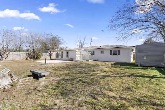 back of house featuring an outdoor structure, a patio, and a lawn