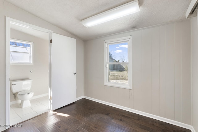 empty room with lofted ceiling, hardwood / wood-style flooring, and a textured ceiling