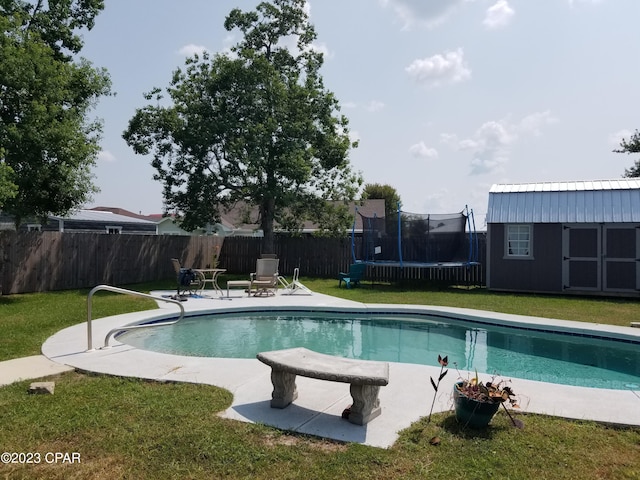 view of swimming pool with an outbuilding, a yard, a fenced backyard, a trampoline, and a fenced in pool