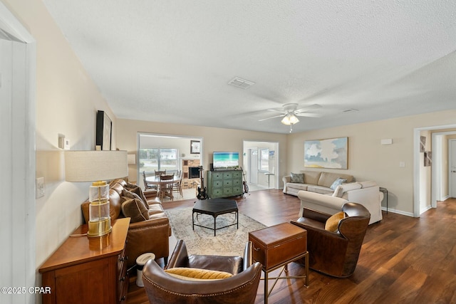 living room featuring a textured ceiling, dark wood-type flooring, and ceiling fan