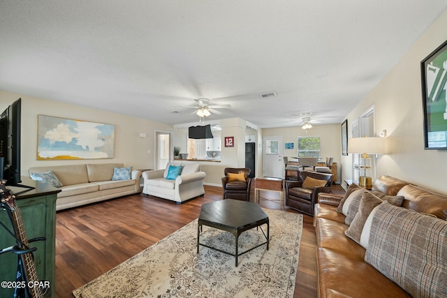 living room featuring dark wood-type flooring and ceiling fan