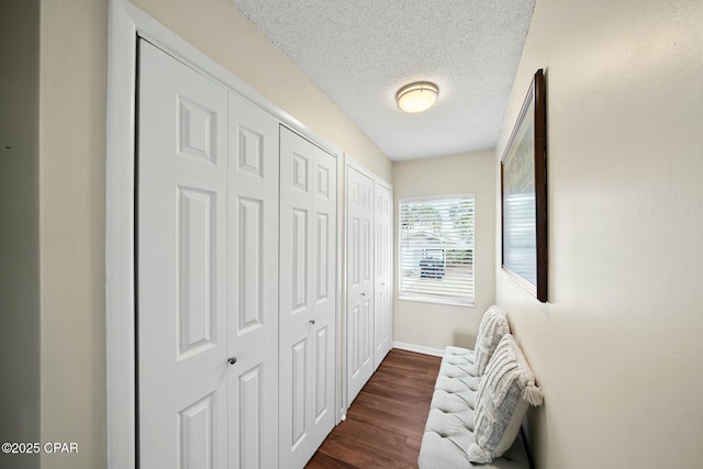 corridor with dark hardwood / wood-style floors and a textured ceiling