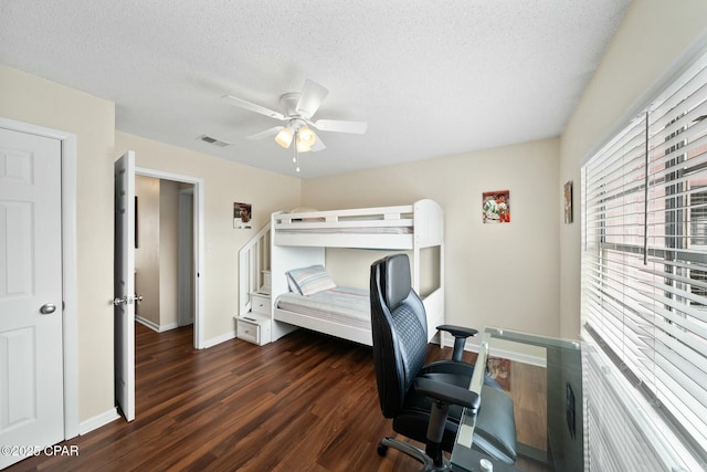 bedroom featuring dark hardwood / wood-style flooring, ceiling fan, and a textured ceiling