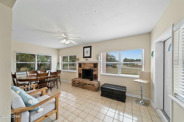 living room with light tile patterned floors, a fireplace, a textured ceiling, and ceiling fan