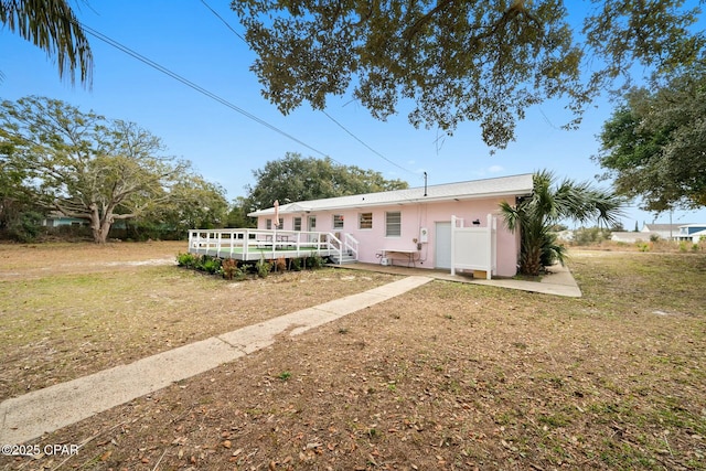 view of front facade featuring a wooden deck and a front lawn