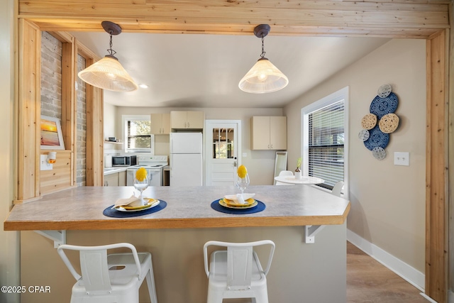 kitchen featuring a kitchen breakfast bar, pendant lighting, and white appliances