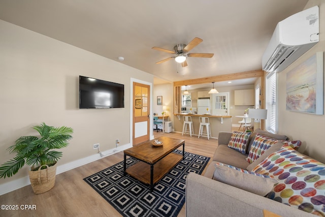 living room featuring a wall mounted air conditioner, light hardwood / wood-style flooring, and ceiling fan