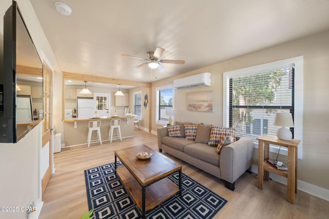 living room featuring ceiling fan, a wall mounted AC, and light wood-type flooring