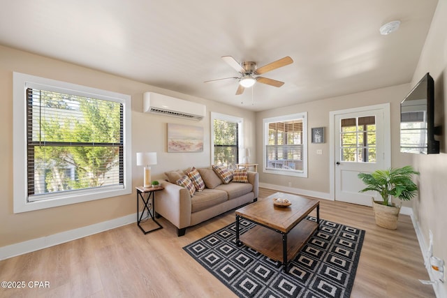 living room with a wall mounted air conditioner, light hardwood / wood-style floors, and ceiling fan