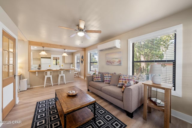 living room featuring ceiling fan, a wall mounted air conditioner, and light hardwood / wood-style floors