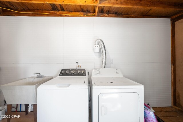 clothes washing area featuring sink, wooden ceiling, and washing machine and clothes dryer