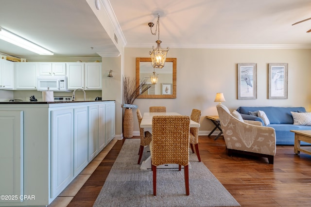 dining area with a notable chandelier, baseboards, dark wood-type flooring, and crown molding