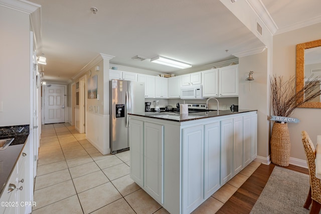 kitchen with white cabinets, dark countertops, ornamental molding, a peninsula, and stainless steel appliances