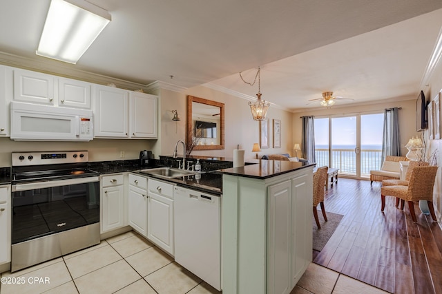 kitchen with open floor plan, a peninsula, white appliances, and a sink