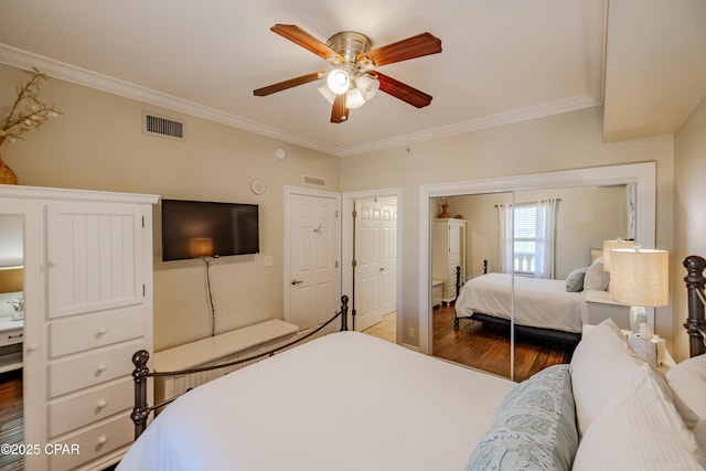 bedroom with ceiling fan, wood finished floors, visible vents, ornamental molding, and a closet