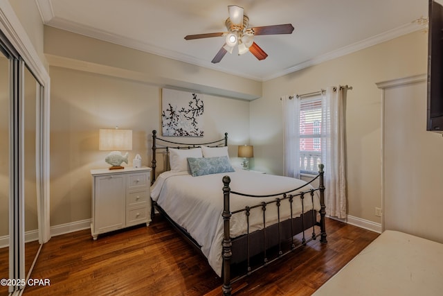 bedroom with a closet, dark wood-type flooring, ornamental molding, a ceiling fan, and baseboards