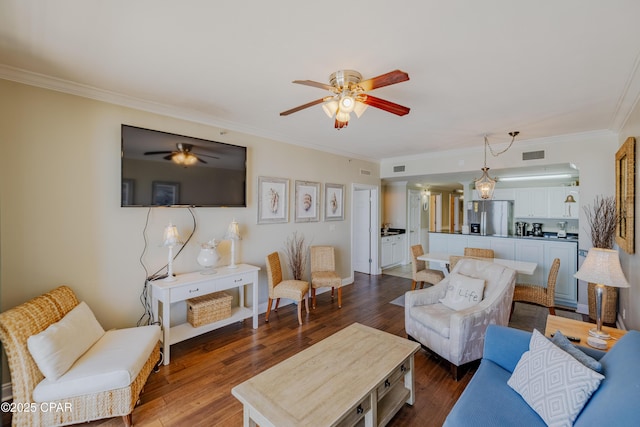 living room featuring a ceiling fan, crown molding, visible vents, and wood finished floors