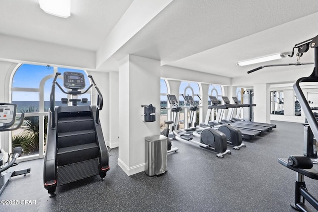 workout area featuring a textured ceiling and baseboards